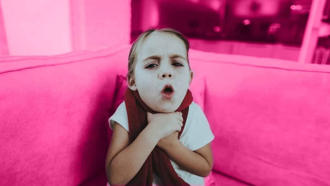 Ni&ntilde;a tosiendo sobre un fondo rosa